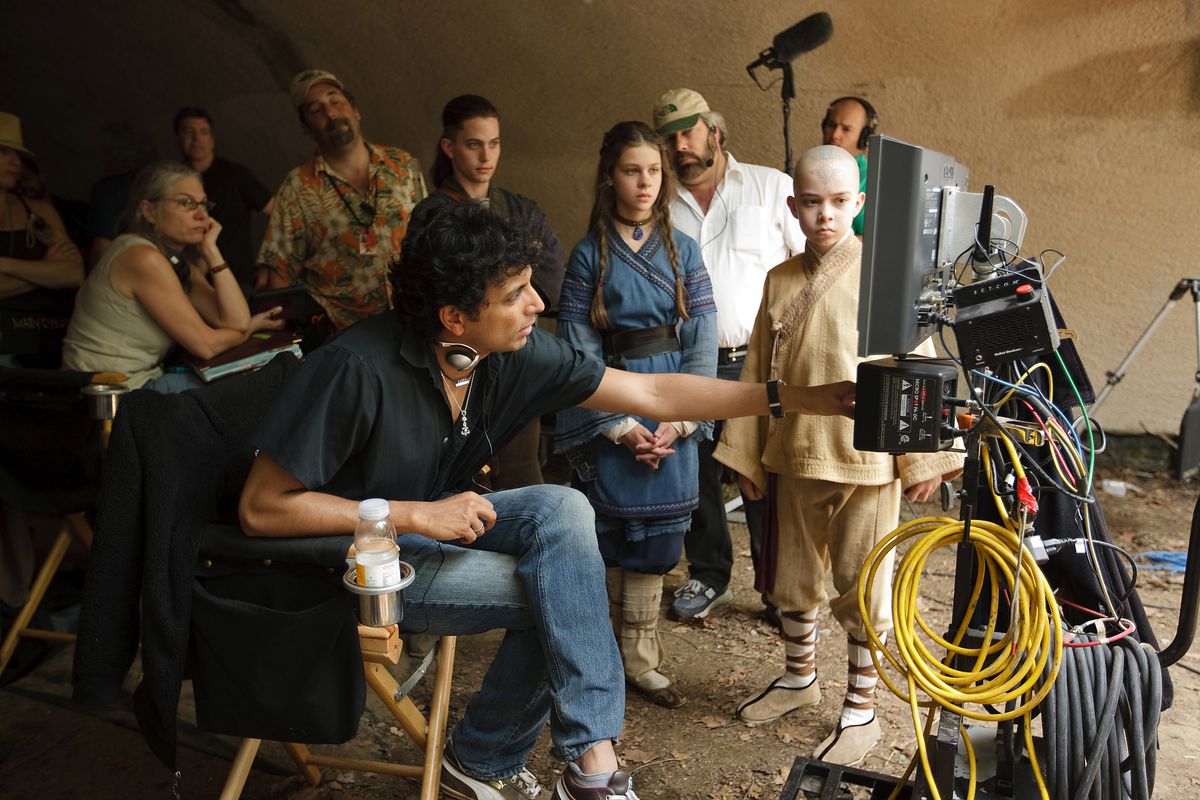 M. Night Shyamalan, Jackson Rathbone, Nicola Peltz, and Noah Ringer on set with The Last Airbender crew looking at a monitor