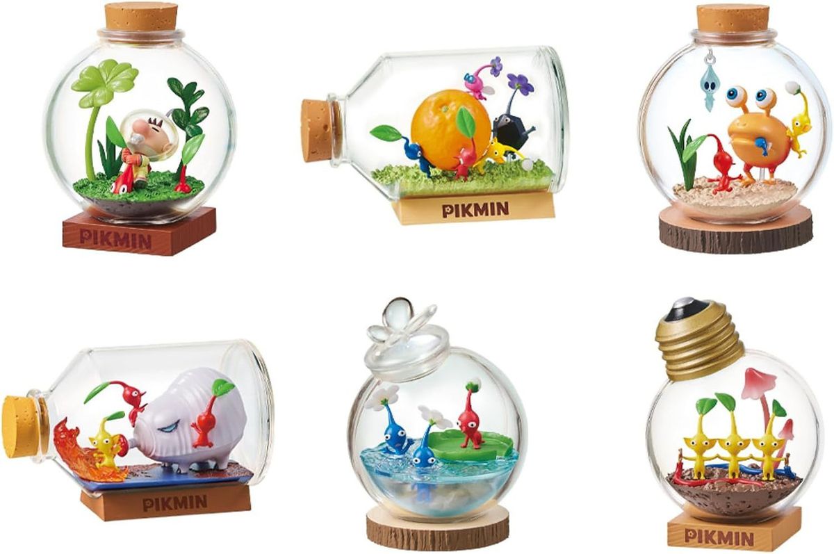 There are six images shown, each representing toys that are included with the Pikmin Terrarium set from Re-Ment. One shows Captain Olimar plucking a Pikmin creature from the ground, one where Pikmin are working together to carry an orange, two where Pikmin are fighting enemy creatures, one where blue Pikmin are swimming as a red Pikmin looks at them, and lastly, one were three yellow Pikmin have joined hands to form a closed circuit that conducts electricity.