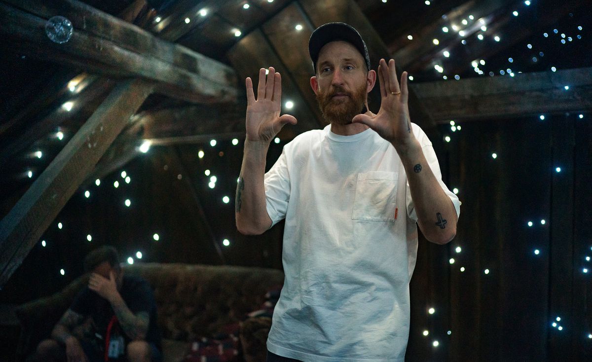 Director Johan Renck, wearing a white T-shirt, stands on a set on his movie Spaceman, in a black space surrounded by naked wooden beams and star-like pinpoints of light