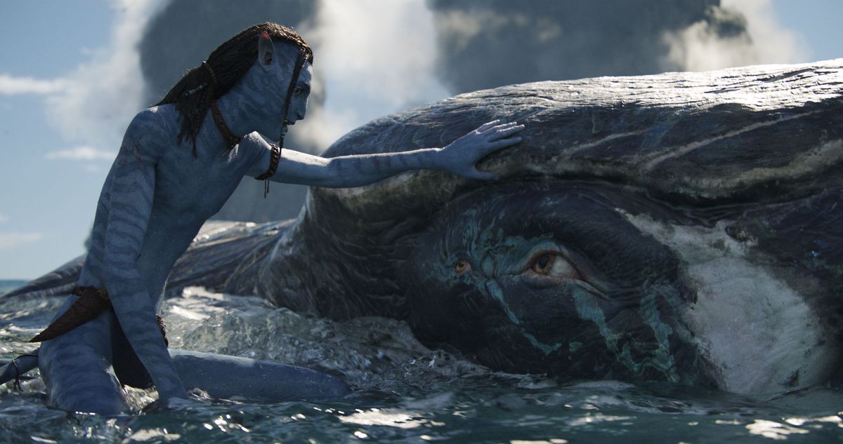 Lo’ak the Na’vi touches a tulkun, a whalelike creature, in the sea of Pandora in Avatar: The Way of Water