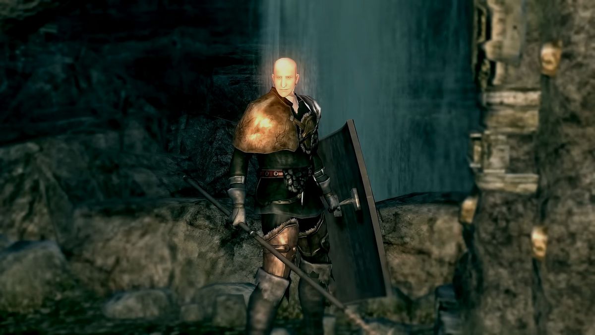 Patches stands next to a bridge lever, with spear and shield in hand, in a screenshot from Dark Souls Remastered