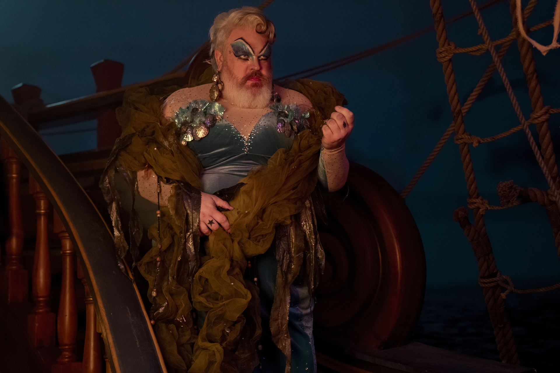 Kristian Nairn as pirate Wee John Feeney in season 2 of Our Flag Means Death, dressed in drag for a nightime sailors’ ceremony honoring the goddess Calypso