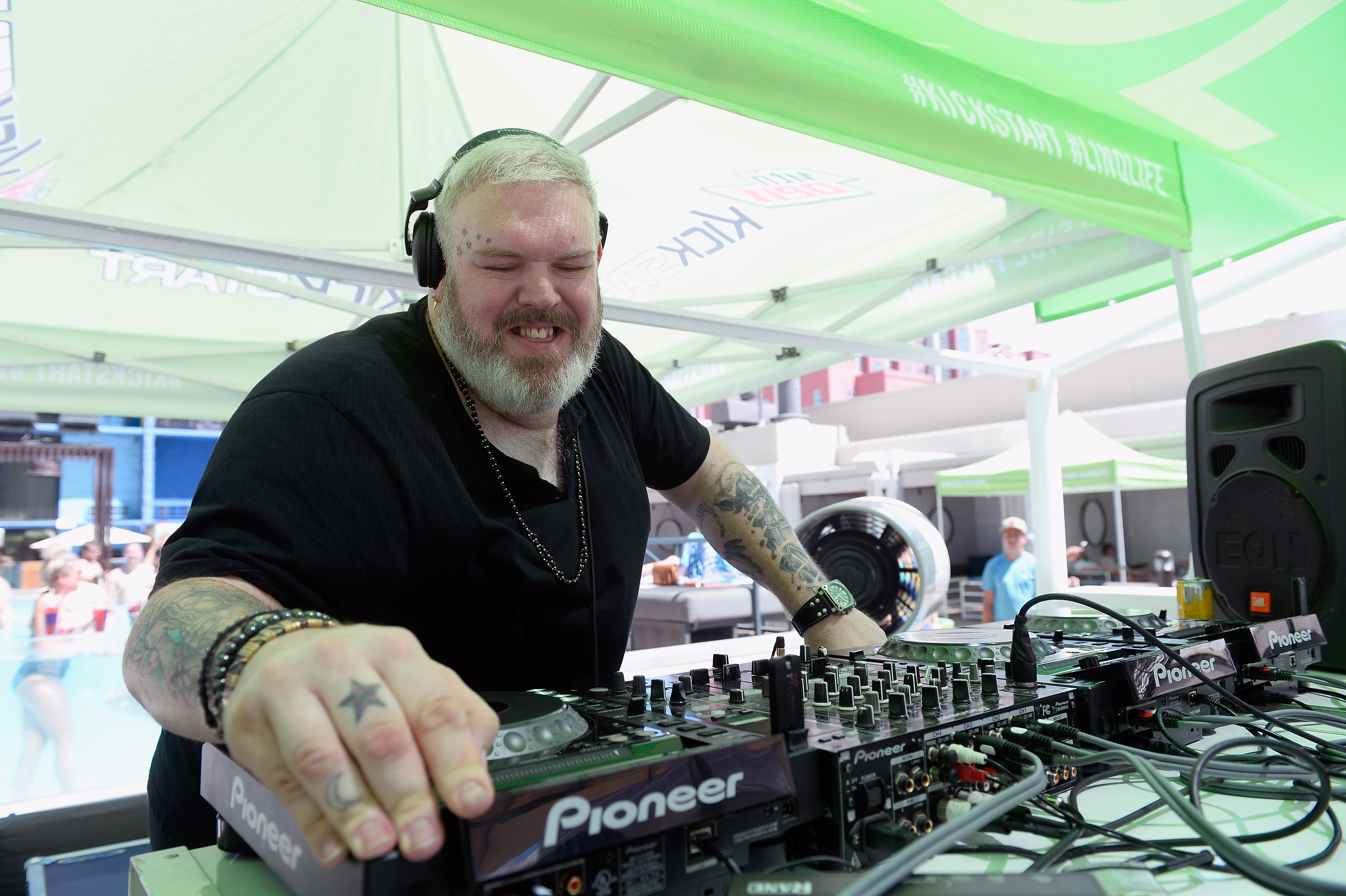 Kristian Nairn DJing at an outdoor Las Vegas event under a white-and-pale-green canopy tent