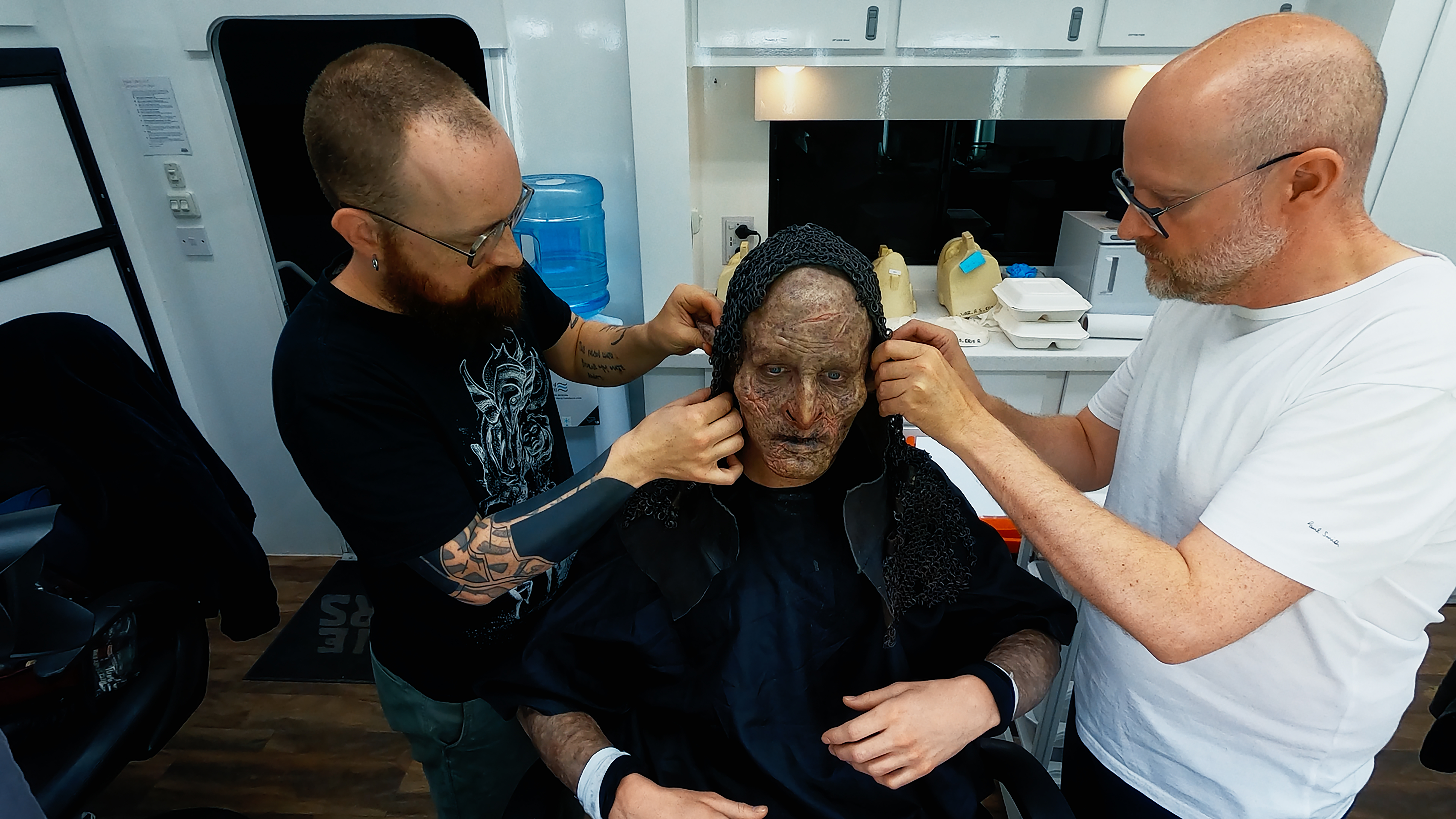 Prosthetics Artist Patt Foad (left); Robert Strange (center); and Prosthetics Designer Barrie Gower putting the balaklava over Robert Strange’s head (with orc makeup on)