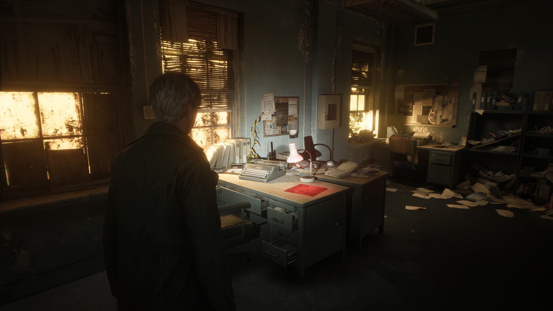 James, the protagonist of Silent Hill 2, faces away from the viewer and looks at a messy office with a desk in it, covered in papers and debris