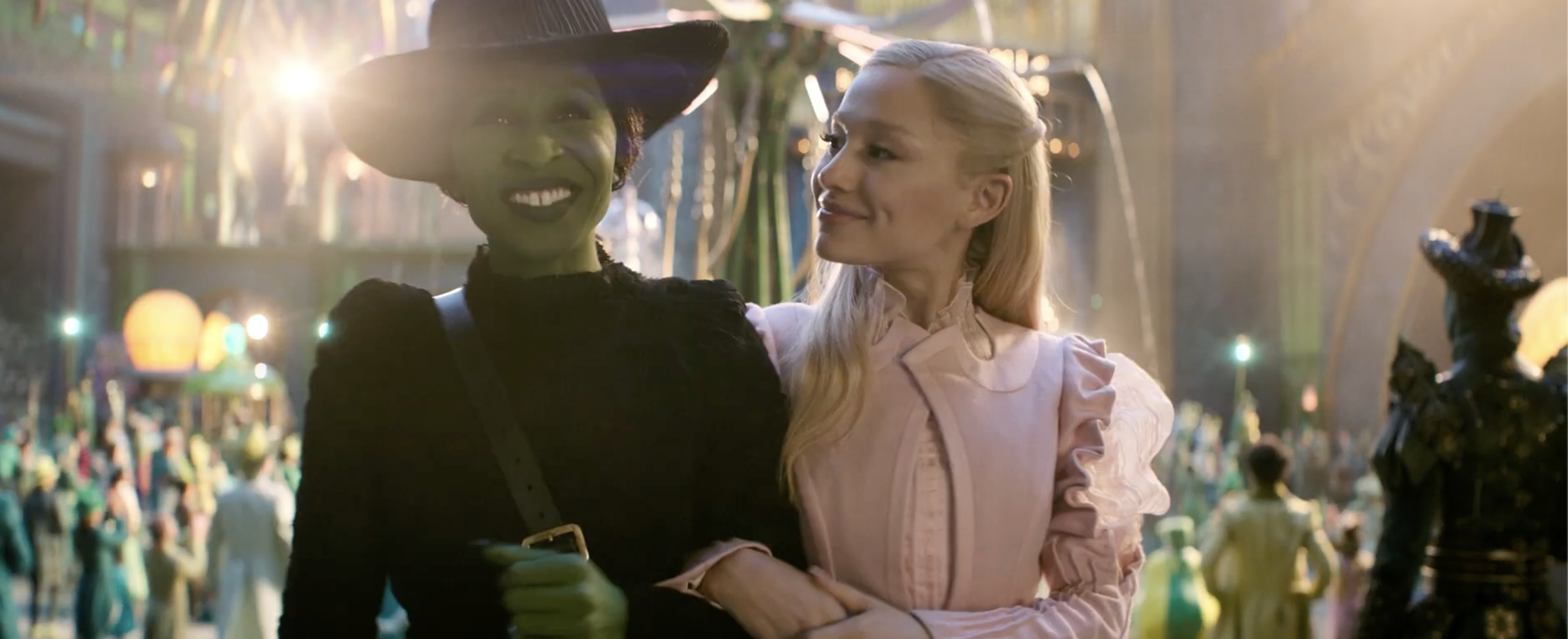 Glinda and Elphaba arm in arm, while walking through the Emerald City in Wicked.