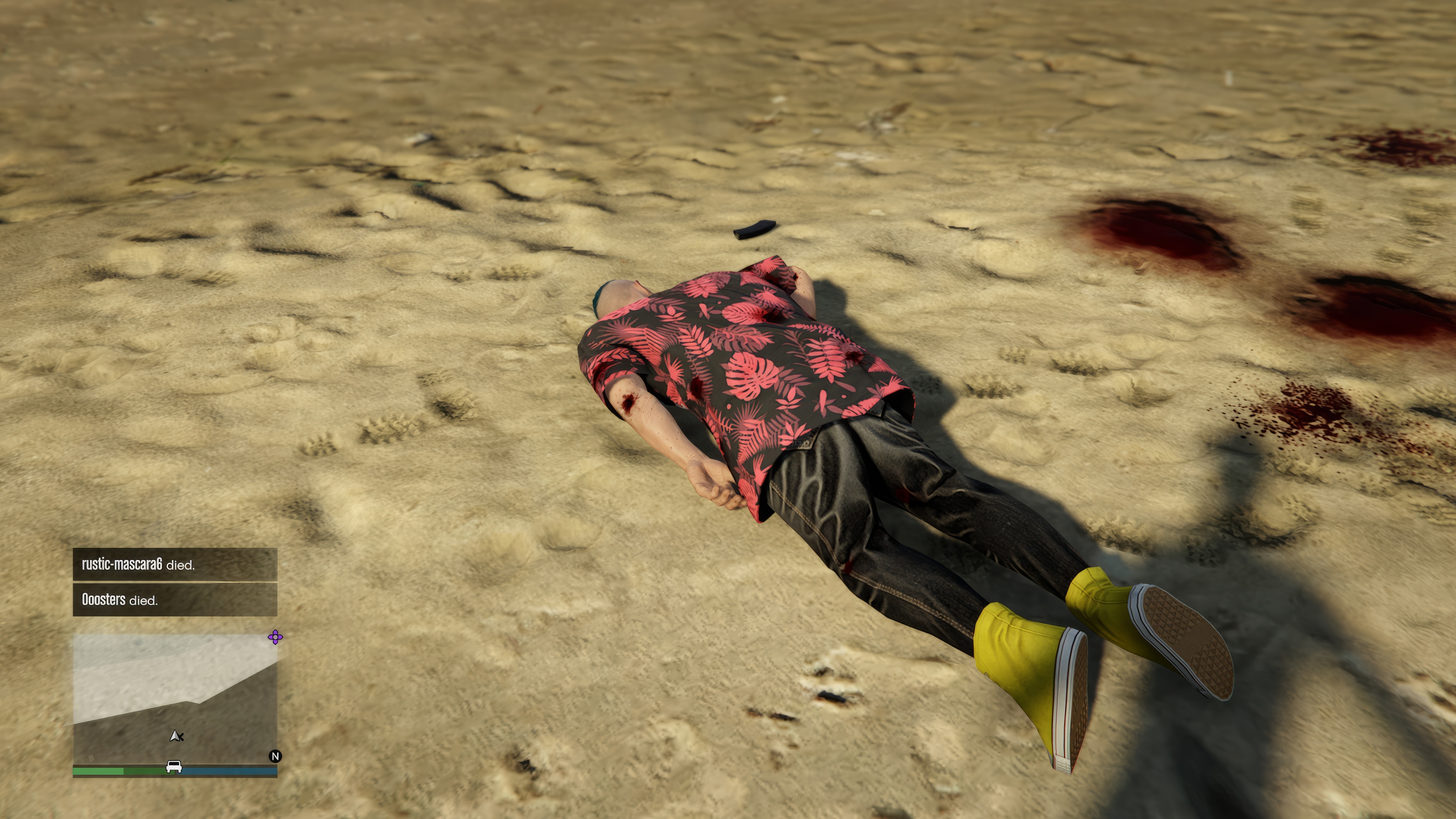 An avatar in a patterned red shirt and yellow high-top tennis shows lies face-down on the ground with blood spattered around the area and a human shadow looming over him in Grand Theft Auto Online, in a scene from Grand Theft Hamlet