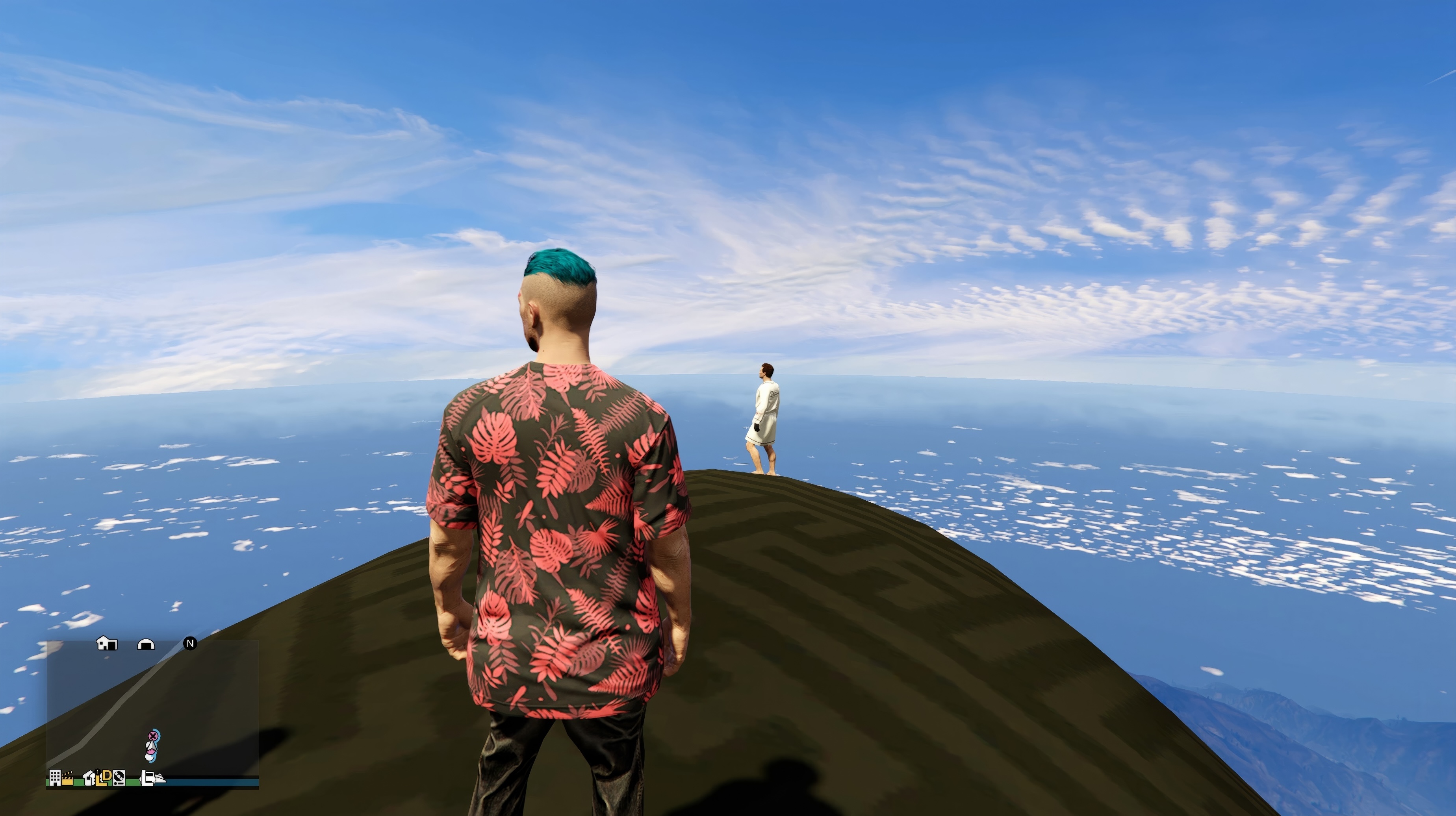 An avatar with blue-green hair and a patterned red-and-black shirt stands on a rocky outcropping above a cloud-streaked blue sky in Grand Theft Auto Online, in a scene from Grand Theft Hamlet