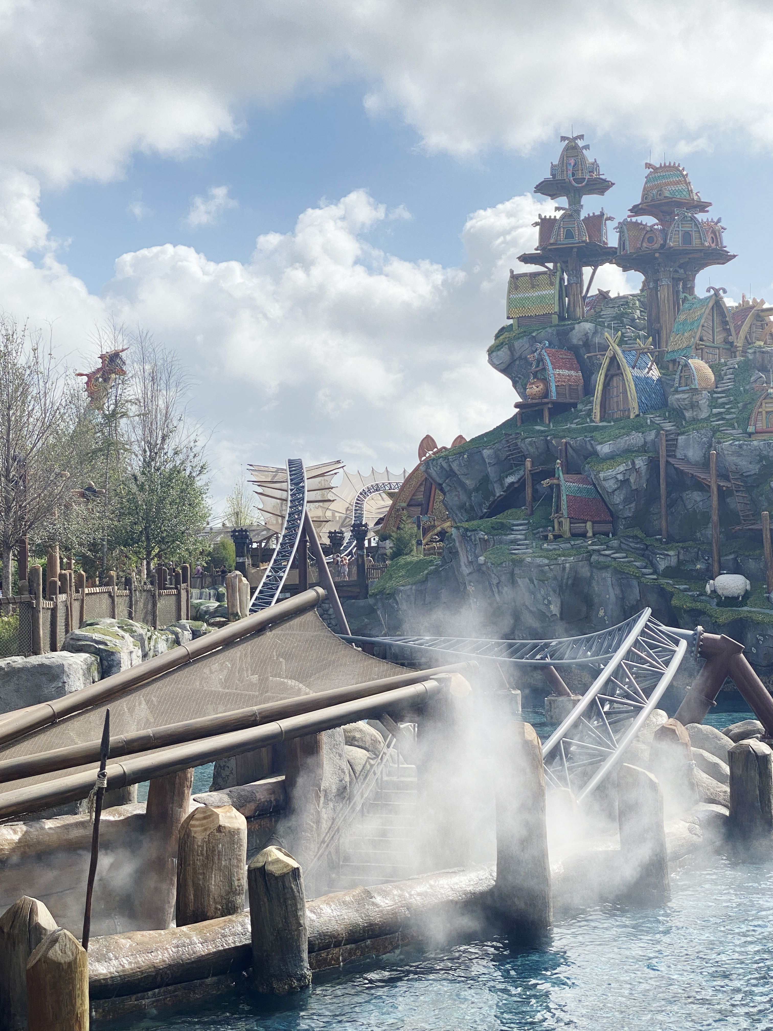 A roller coaster track built along a lagoon and dragon shelter complex at How to Train Your Dragon land at Epic Universe