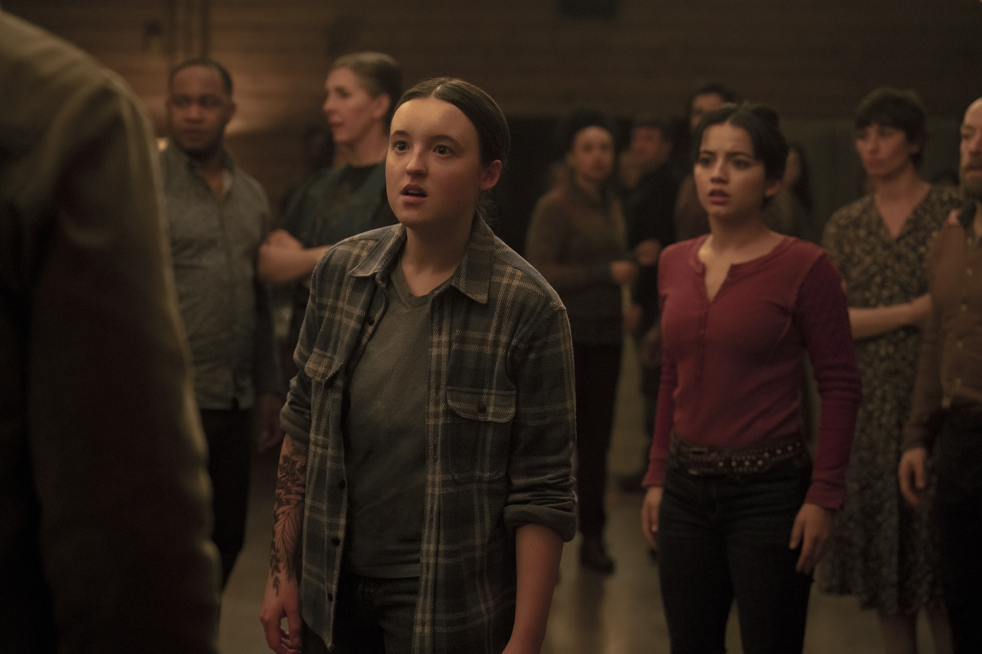 Bella Ramsey and Isabela Merced as Ellie and Dina in The Last of Us season 2. They’re standing on the dance floor in Jackson looking shocked and upset.