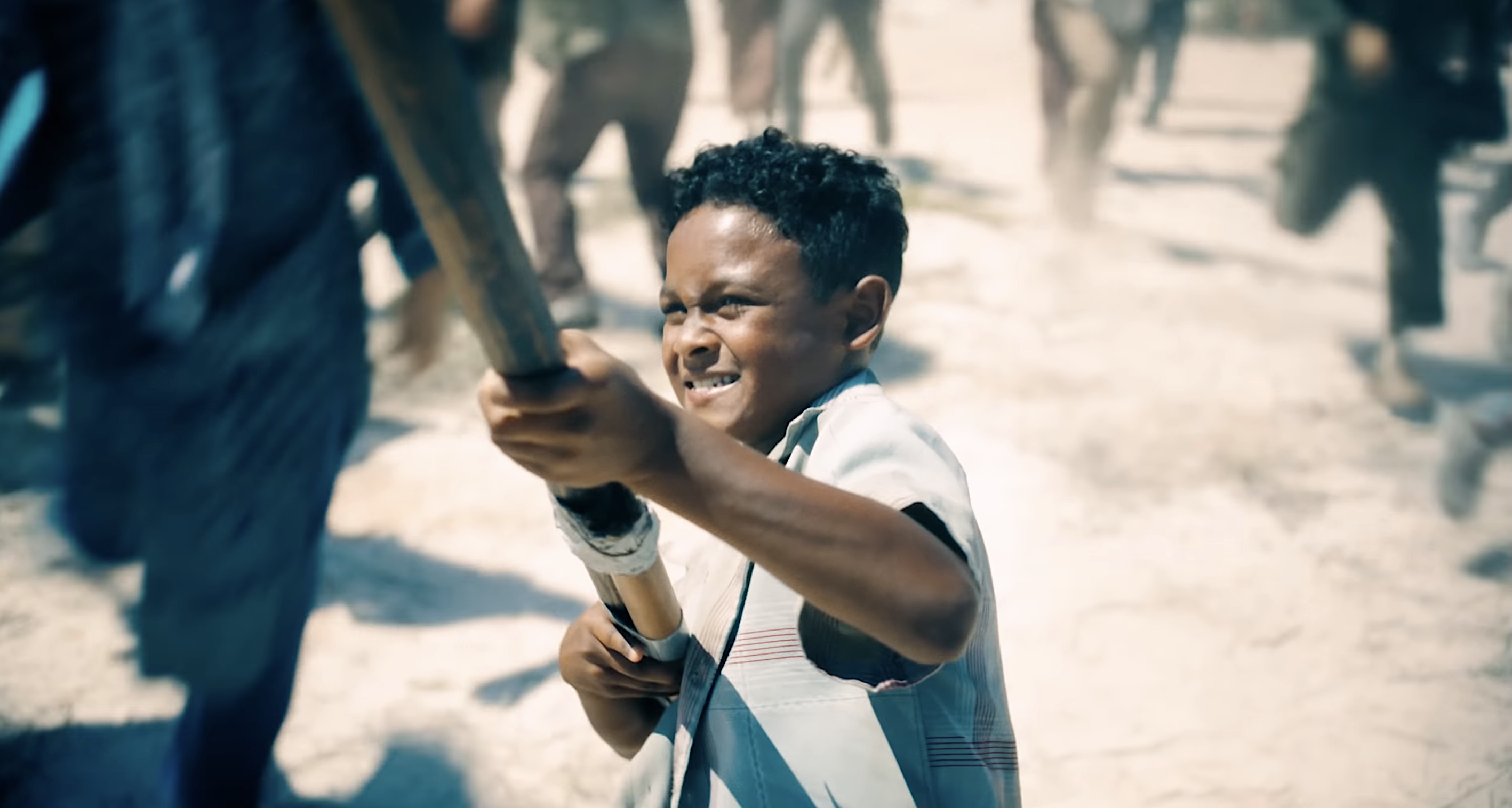A dark-skinned, dark-haired, thin kid in a shapeless tunic struggles to raise a flagpole on a battlefield in James Gunn’s Superman