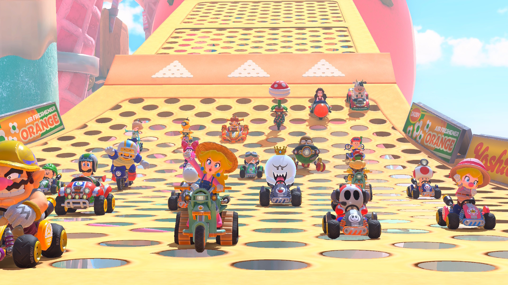 A full set of 24 racers in Mario Kart World, with Peach and Wario in the lead